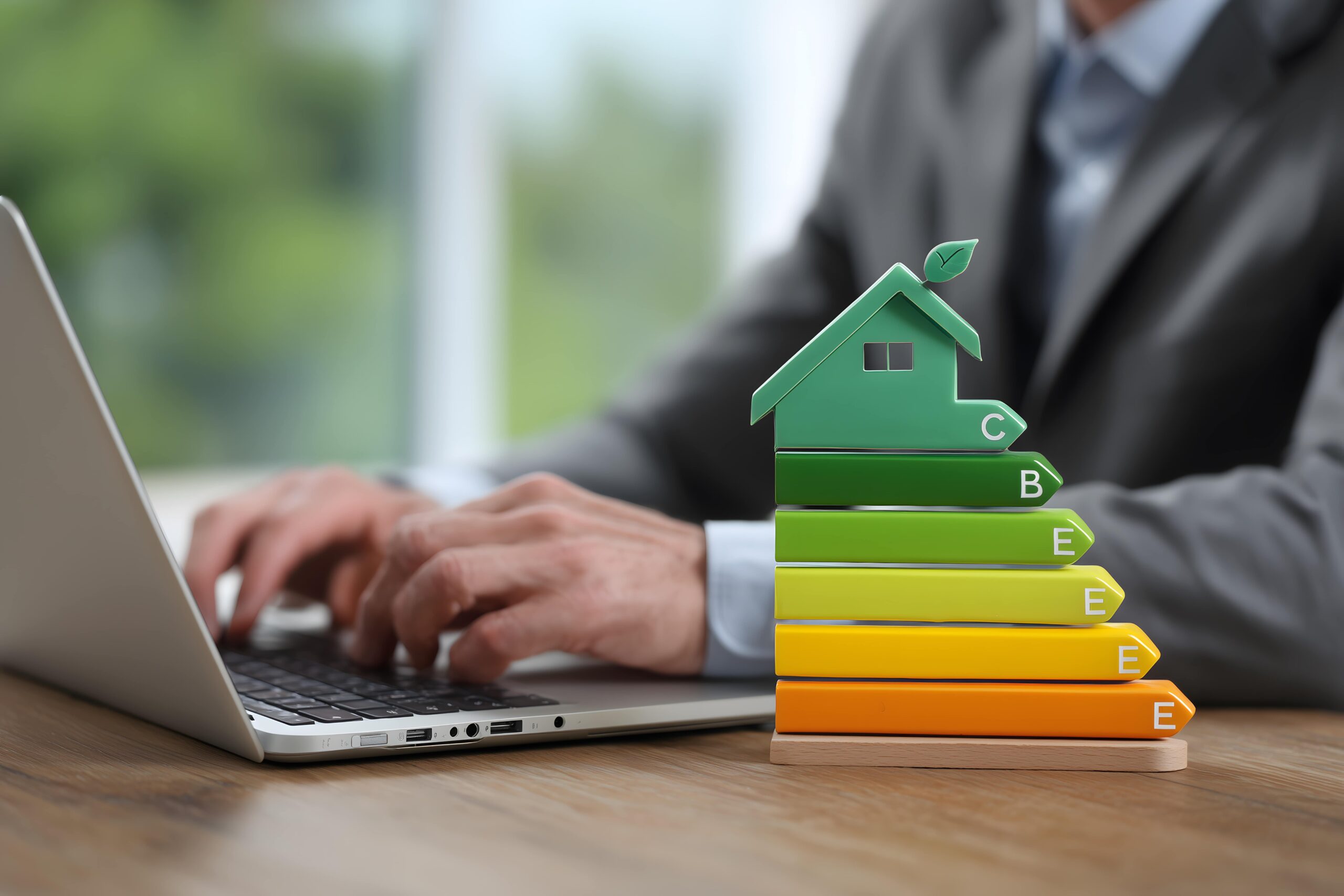 Colorful energy efficiency rating chart displayed on a miniature house model, accompanied by thriving plants, symbolizing eco consciousness and sustainable housing